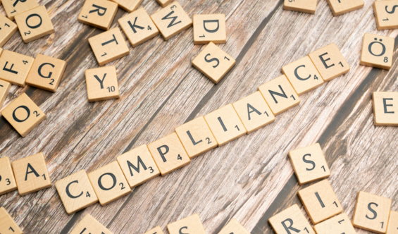 the-word-compliance-spelled-out-with-wooden-letter-tiles-on-a-rustic-table.jpg The word compliance spelled out with wooden letter tiles on a rustic table